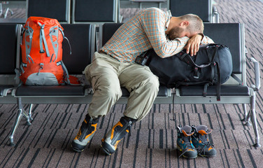 Difficult journey.
Man sleeping on his luggage lean onto large backpack heavy winter boots and...