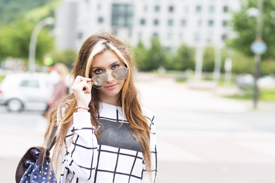 Hipster young woman with sunglasses and backpack in the street.