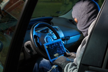 Car thief stealing a car. Hacking into the car system.