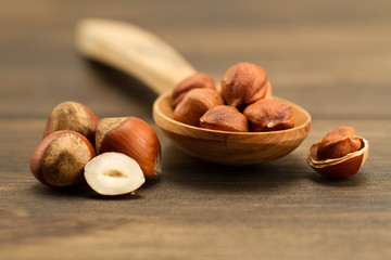 shelled hazelnuts in spoon on wooden background, close up