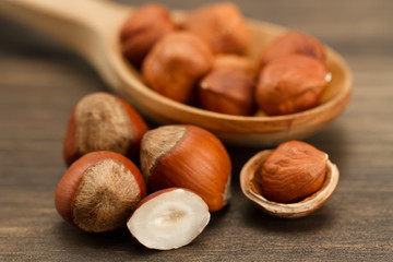 shelled hazelnuts in spoon on wooden background, close up