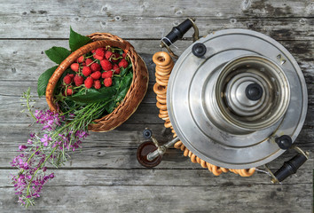 russian samovar on a rustic wooden table with berries and flowers