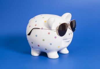 Piggy bank with sunglasses on blue background