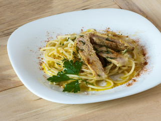 Pasta with meat, olive oil, fresh herbs and red pepper on a white plate