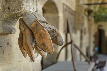 A group of antique wooden shoe forms hanging in an outdoor Mediterranean market.