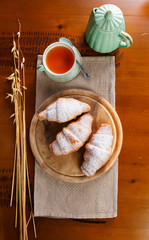 Croissant served on wooden plate with tea