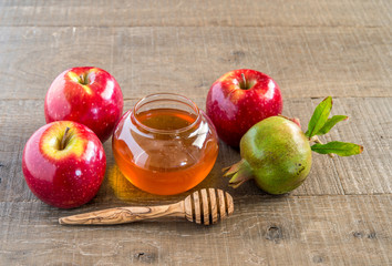 Honey, apples and pomegranates on wood deck for Rosh Hashana celebration.