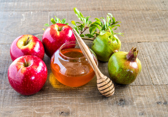 Honey, apples and pomegranates on wood deck for Rosh Hashana celebration.