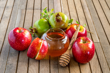 Honey, apples and pomegranates on wood deck for Rosh Hashana celebration.