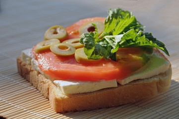 Toast loaded with feta cheese, oxheart tomato slice, olive slices and lettuce leaf basil 