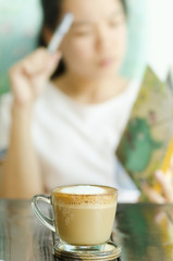 The cup of coffee on the table with woman working background