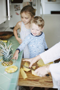 Woman cutting a fresh pineapple for her children.