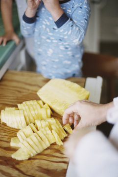 Woman cutting a fresh pineapple for her children.