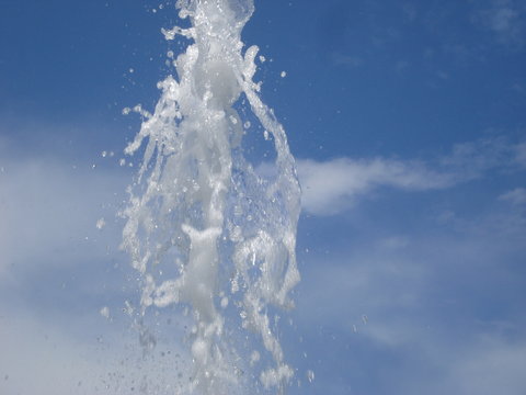 Water spirting from artesian well, on blue summer sky