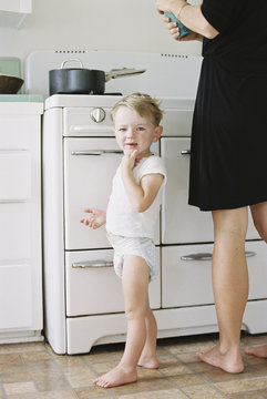 A woman and a child, a young boy standing barefoot in a kitchen.