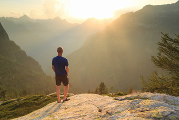 Male hiker enjoying the sunset in the mountains of  Ticino, Switzerland.