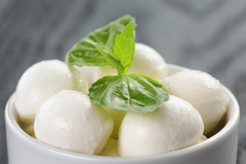 Fototapeta na wymiar small balls of mozzarella in bowl with basil