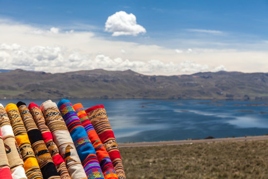 Tessuti tipici colorati del Sud America. Peru e Bolivia.  Lago e montagne con nuvole bianche sullo sfondo
