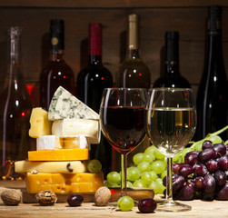 Wine with various types of cheese on wooden background