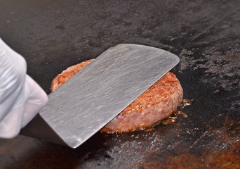 Cocinando carne de hamburguesa en una plancha.