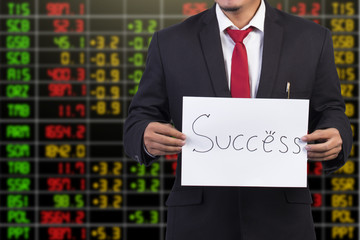 Businessman showing success word on stock market background