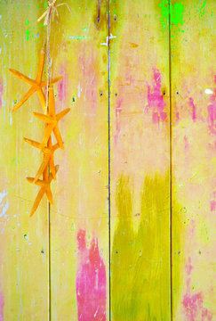 Yellow colorful vintage background with shabby distressed grungy texture hippie style decorated with yellow starfish hanging from a straw string. 