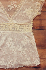 vintage white crochet lace top with hanger on wooden background
