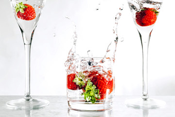Strawberries in a glass filled with water, taken in the studio on a white background.