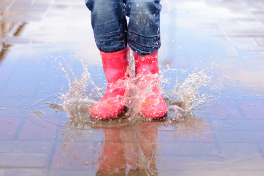 The girl in pink boots jumping in puddles