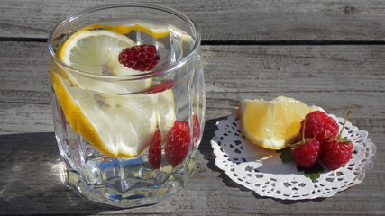 Вкусный коктейль и салфетка с кусочком лимона и ягодками малины 