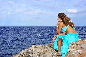 Fototapeta na wymiar woman looking at sea horizon thoughtful from rock cliff in relax concept