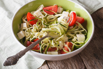 zucchini spaghetti with feta and tomatoes in a bowl. horizontal 
