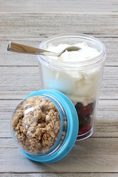 Joghurt mit Müsli und frischen Beeren in einem Picknickbecher