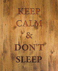 Text "Keep Calm & Don't Sleep" engraved in wooden background