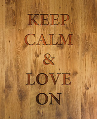 Text "Keep Calm & Love On" engraved in wooden background