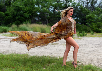 Fashion outdoor photo of beautiful blond woman in luxury animal print resort dress.