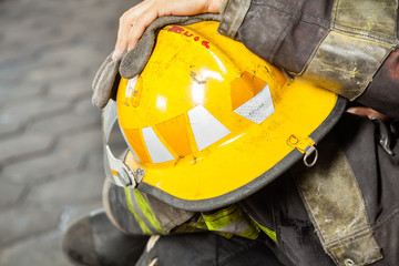 Fototapeta premium Firefighter Holding Yellow Helmet At Fire Station