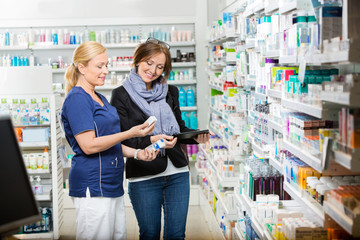 Chemist Showing Eye Drops To Customer Holding Digital Tablet - Powered by Adobe