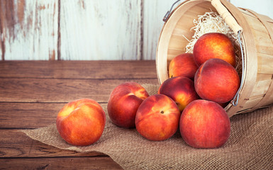 Fresh peach fruits in a basket, rustic wooden background
