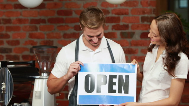 Waiter and customer holding a board with open sign