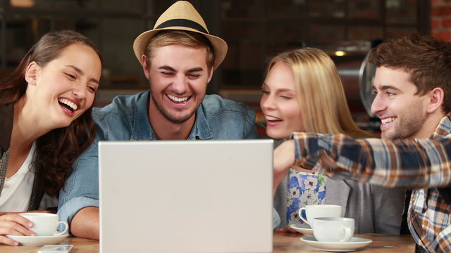 Smiling hipster friends laughing over a laptop