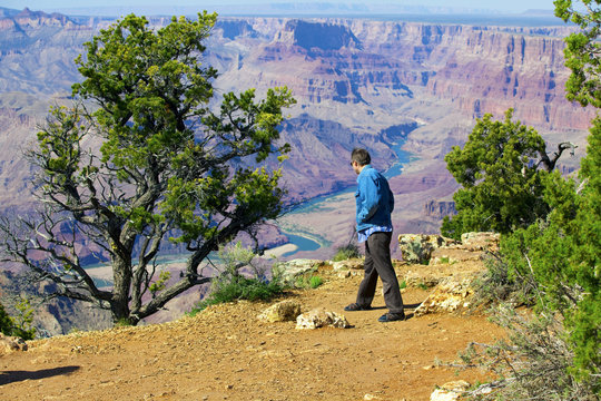 Caucasian Man In Mid Forties Cautiously Looking Over Cliff At Gr