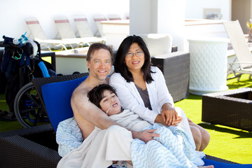 Father and mother with disabled son on blue lounger off side of