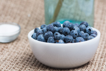 Blueberries in a bowl.  Blue jar and bowl of sugar in the background