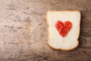 Fototapeta na wymiar slice of bread with strawberry jam in heart shape