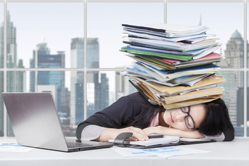 Tired female worker with paperwork on head