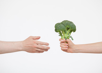 Naklejka na ściany i meble Female hand giving fresh broccoli to somebody