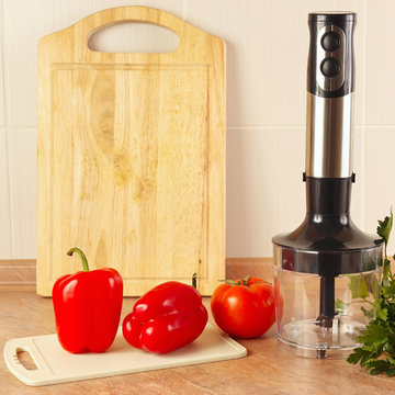 Red bellpepper with tomato and a blender on the kitchen table