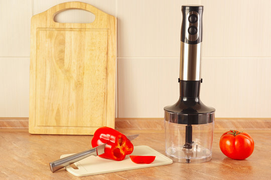 Chopped red pepper with tomato and a blender on the kitchen table