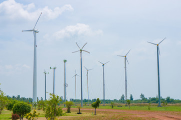 Field of white wind turbines generating electricity on blue sky